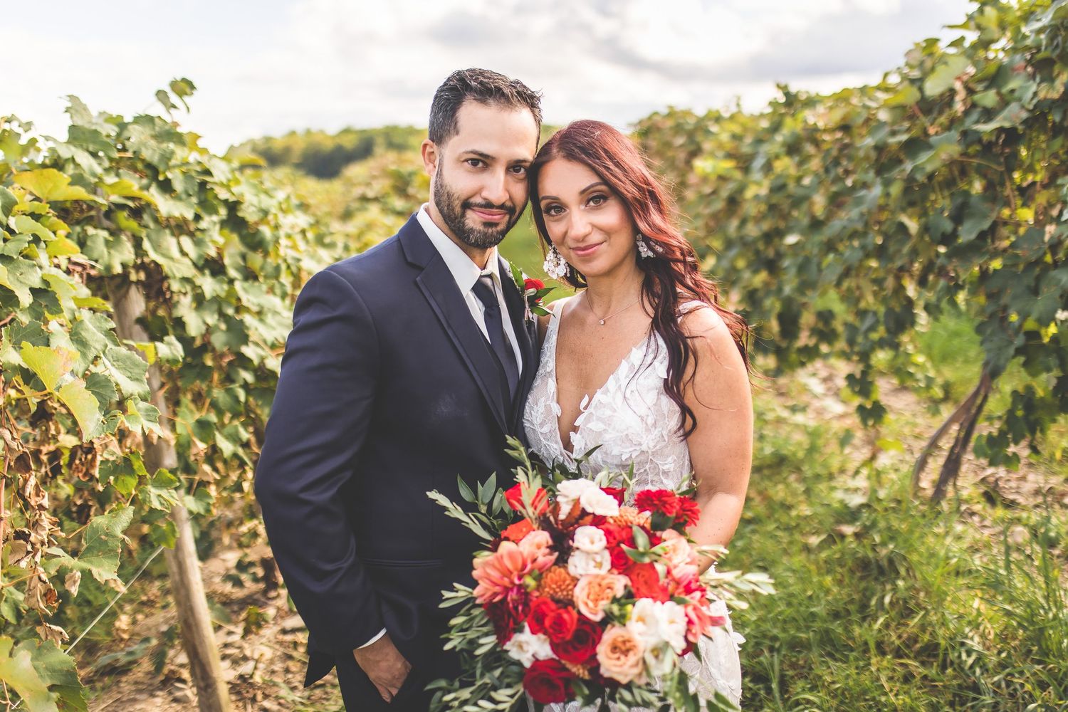 Newlyweds share an intimate moment among rows of grapevines on their wedding day.