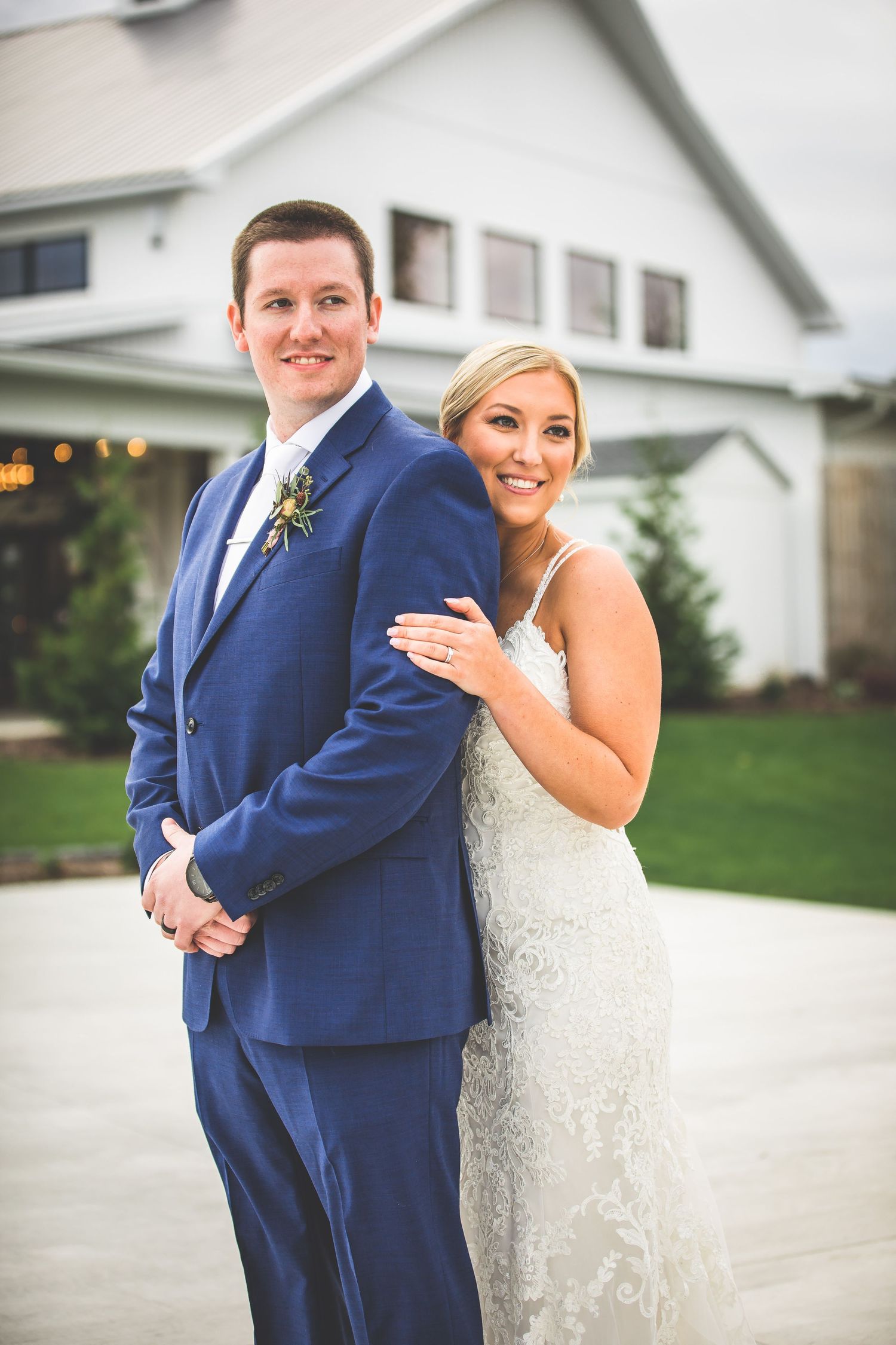 Wedding couple poses playfully outside white building for first look photos.