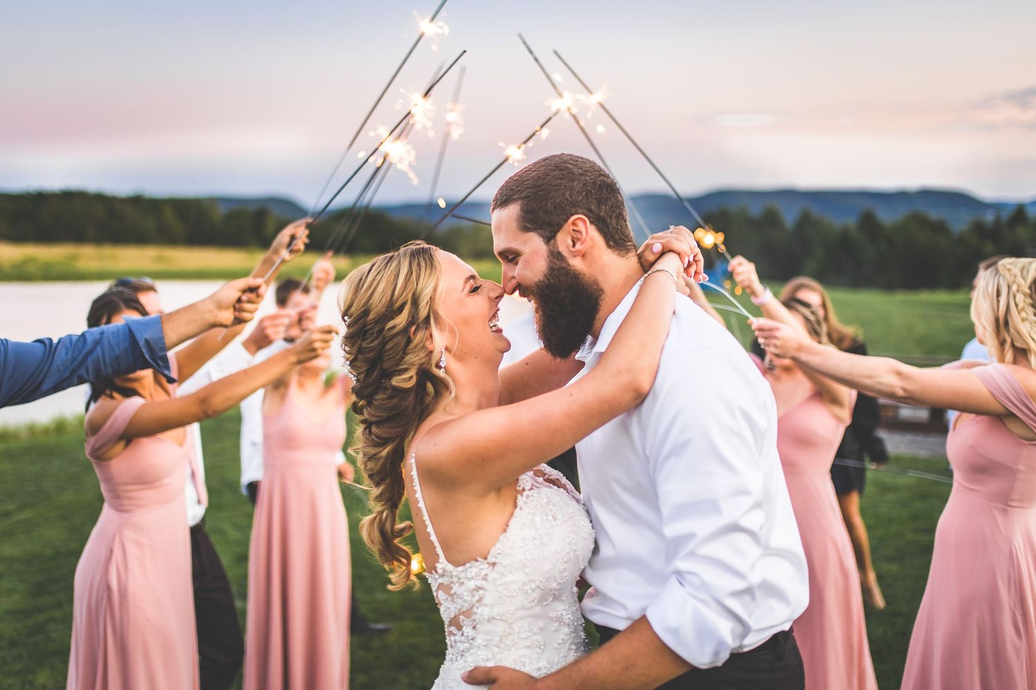 Wedding sparkler exit with couple walking through tunnel of lights at sunset.