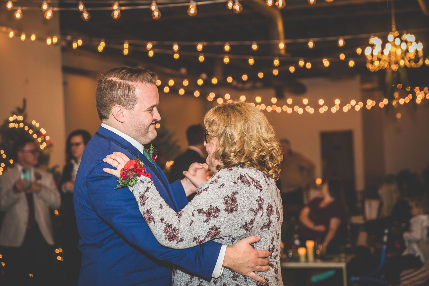 Couples share dances under romantic string light decorations at wedding celebration.