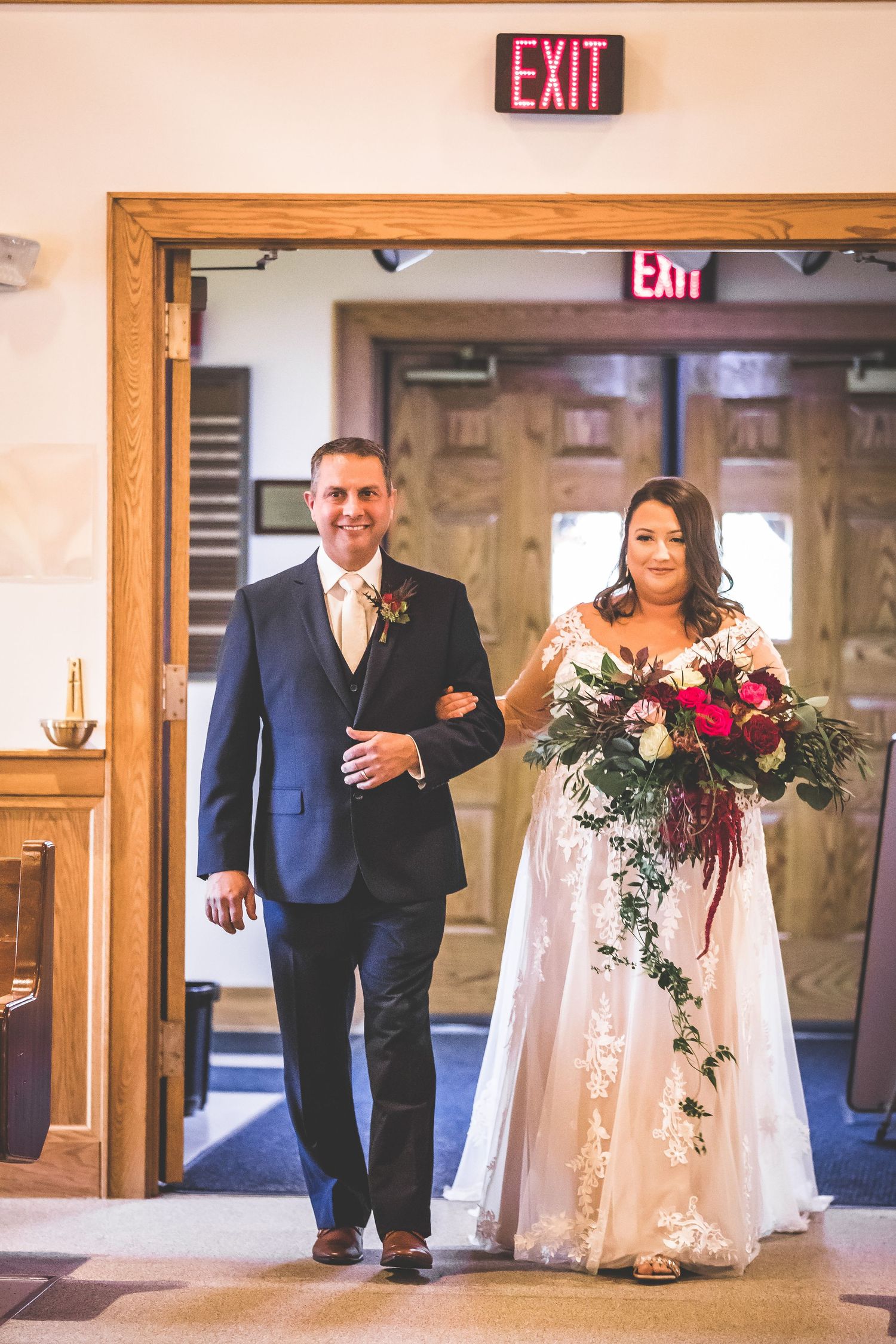Wedding processional walking down church aisle with floral bouquets.