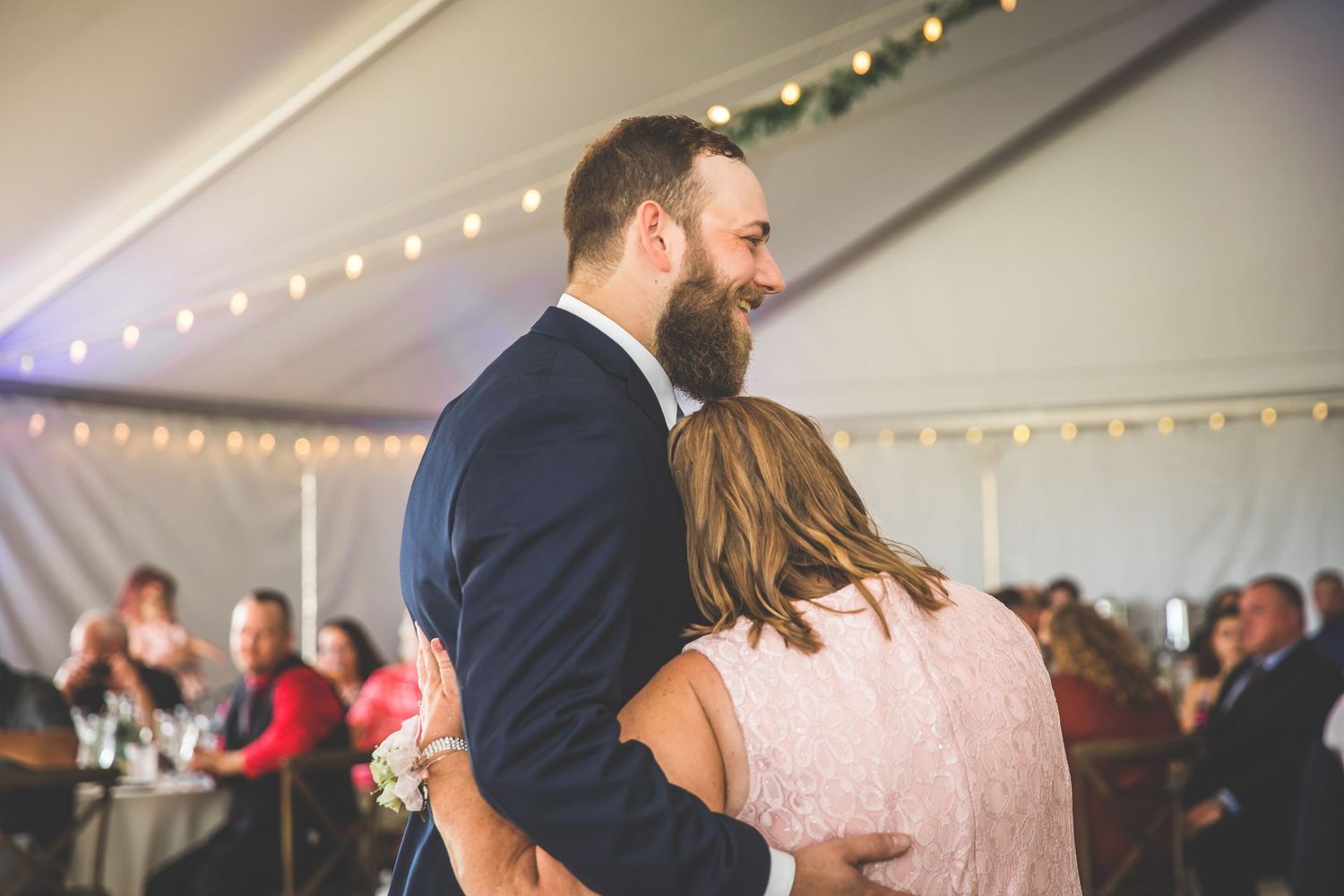 Couples dancing together at a wedding reception under twinkling lights and white tent decor.