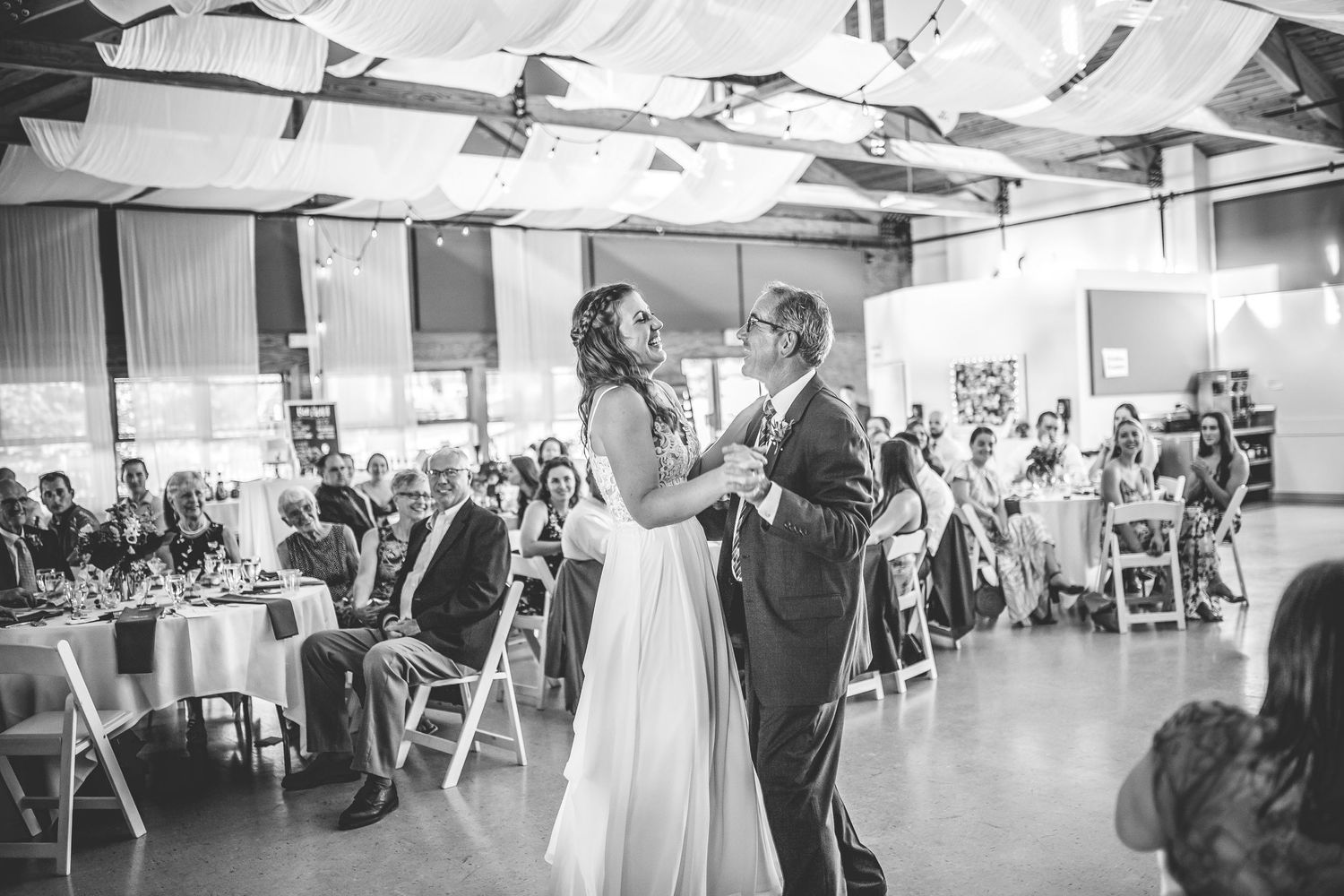 Panoramic view of wedding reception venue with white chairs and ceiling decorations.