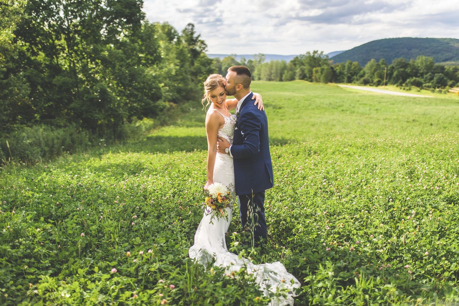 Rolling green hills and cloudy skies create a stunning backdrop for outdoor wedding photography.