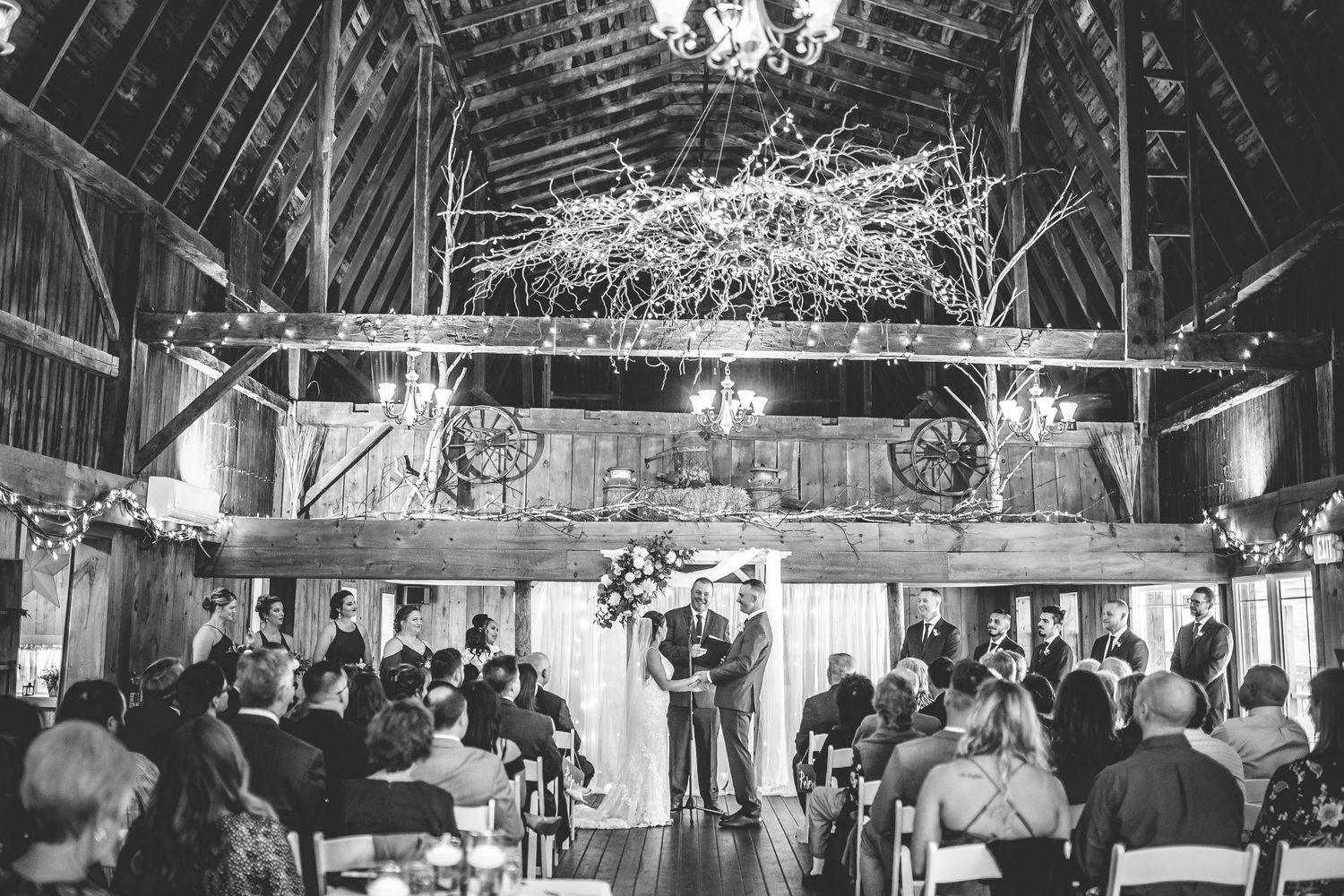 Panoramic view of barn wedding reception with exposed beams and elegant lighting.