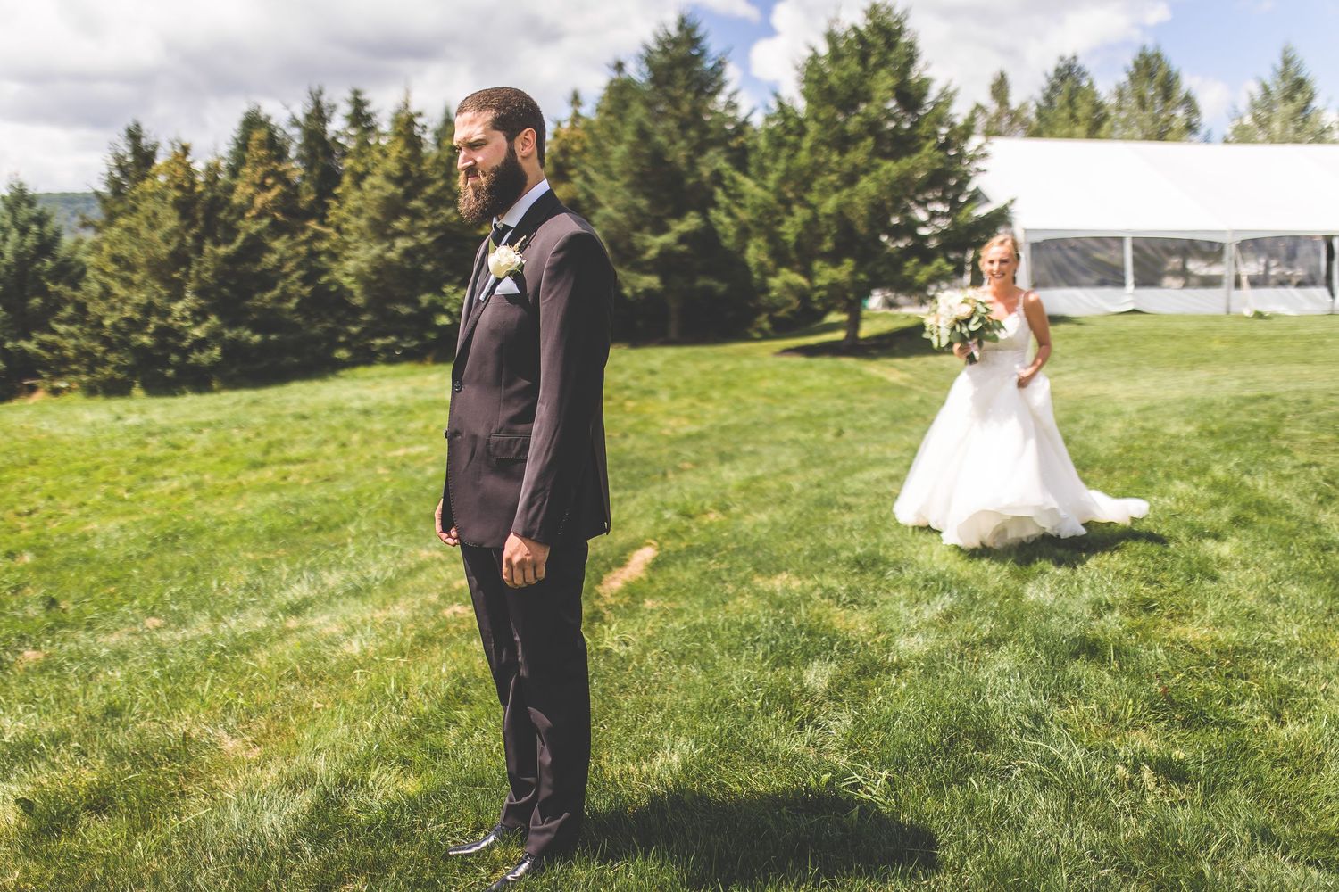 Wedding couple's first look moment in scenic outdoor setting with evergreen trees.