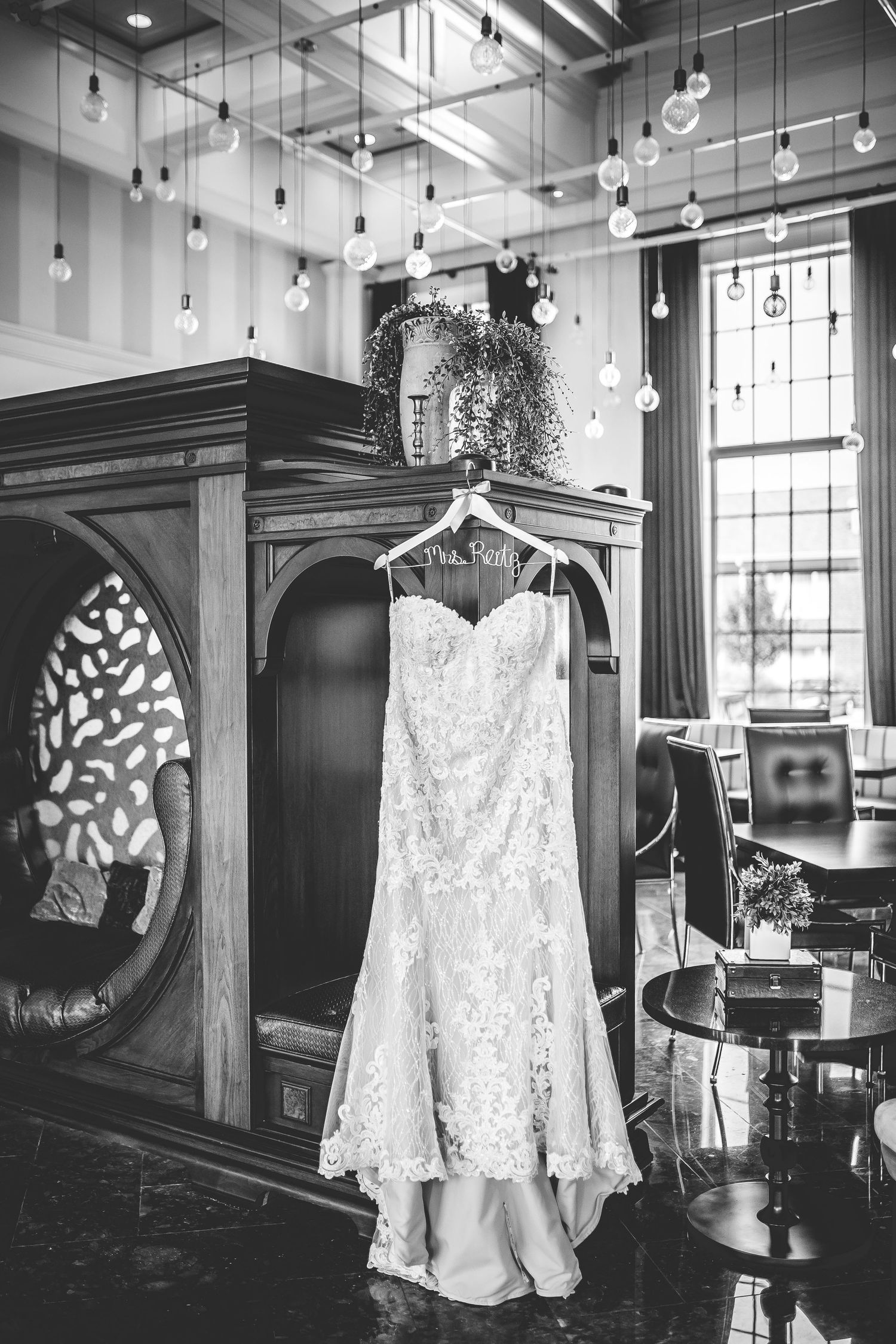 Wedding dress and formal attire displayed in vintage wardrobe with pendant lighting.