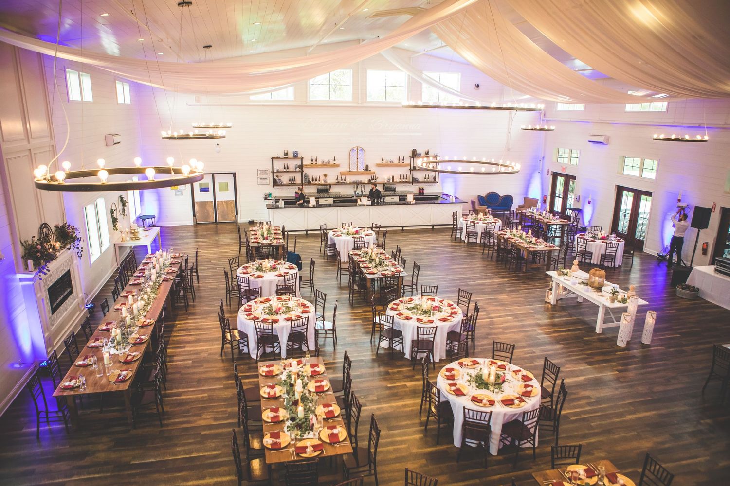 Modern wedding reception venue with white tables and blue uplighting creating an elegant atmosphere.