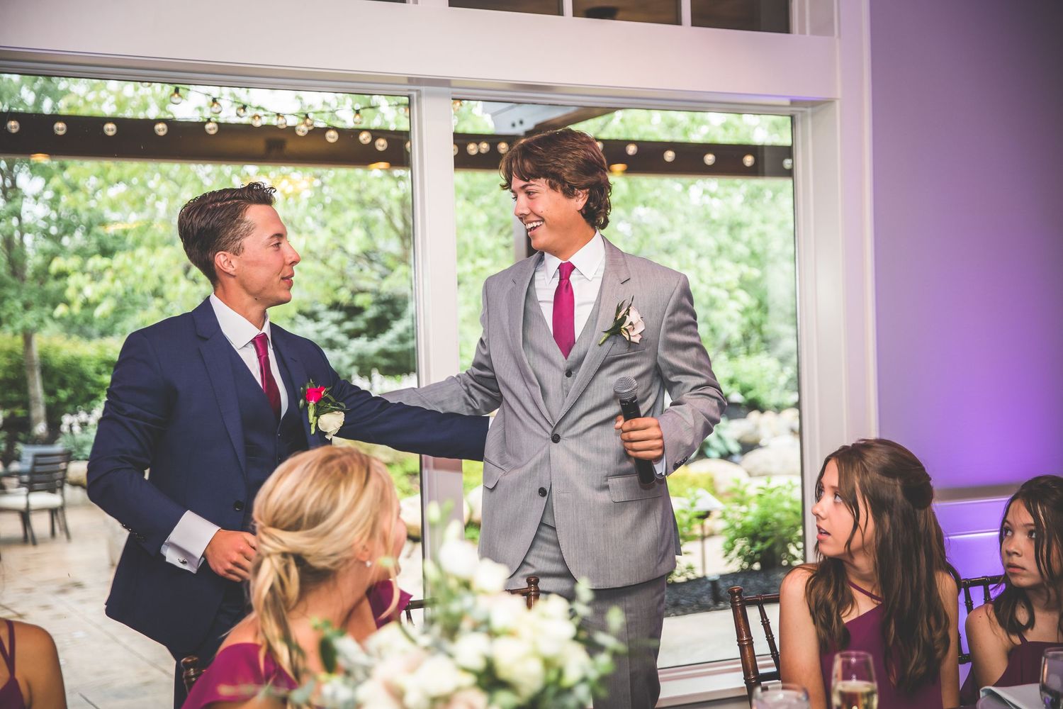 Wedding reception venue with elegant table settings and purple uplighting creating a romantic atmosphere.