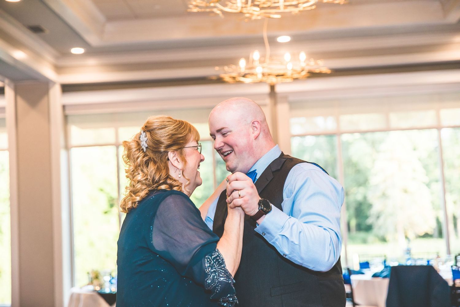 Wedding reception guests enjoying a celebration in an elegant ballroom with chandeliers.