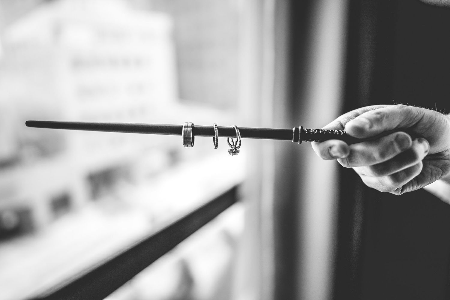 Hand holding a magic wand against blurred background in black and white.