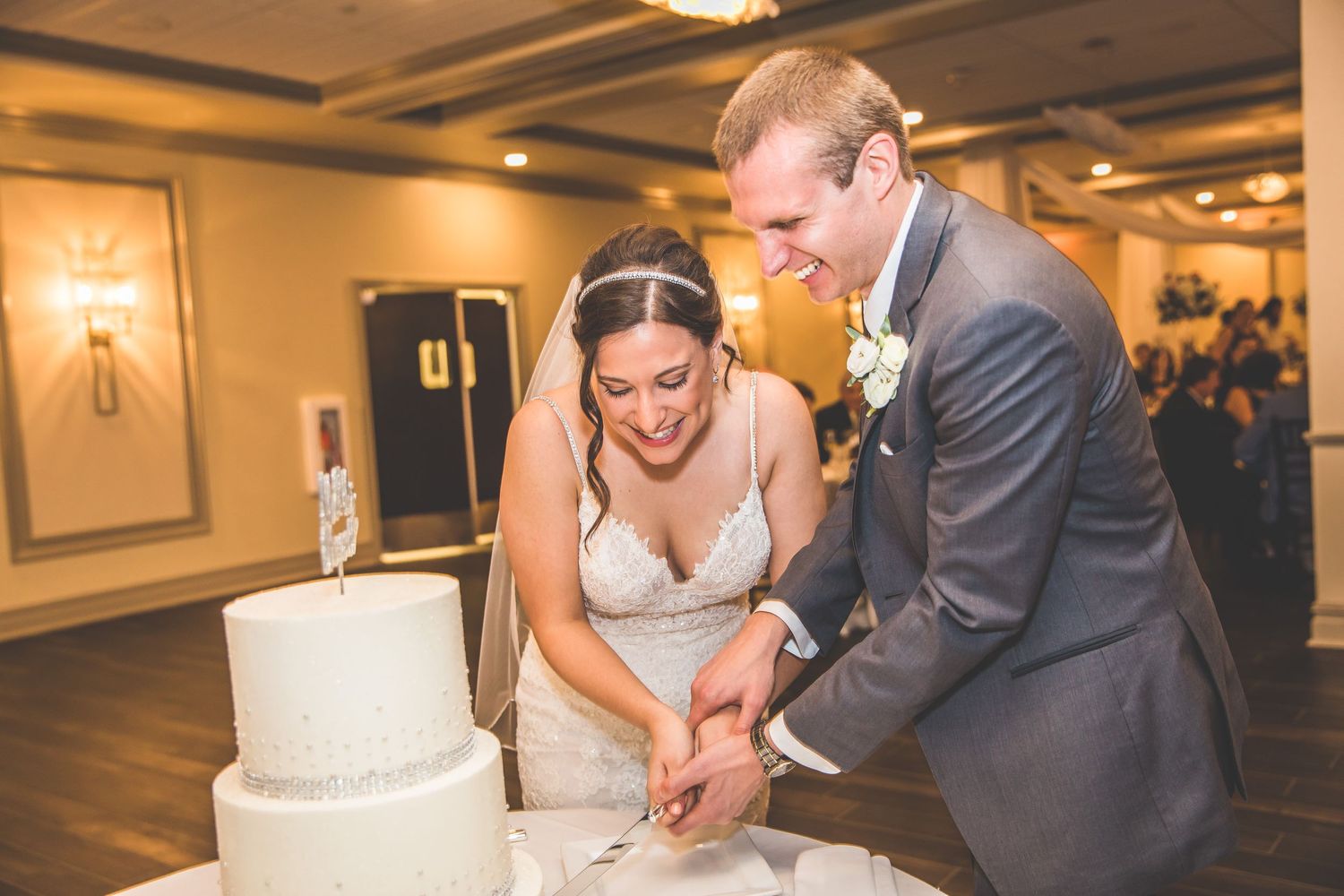 Couple cuts their wedding cake together at an elegant indoor reception.