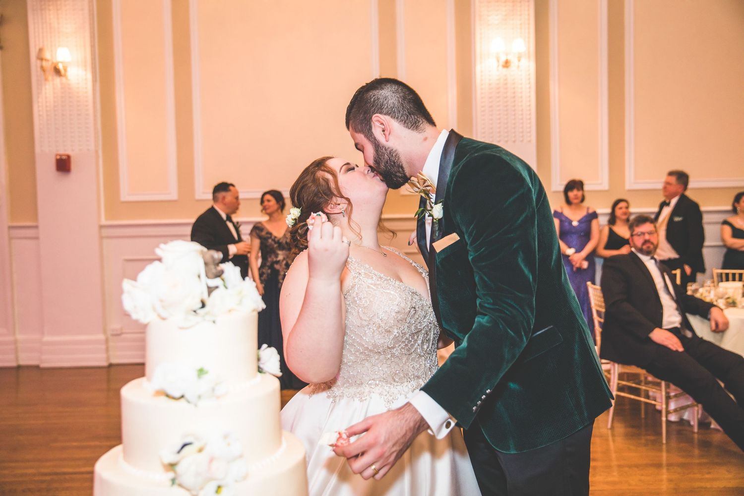 Wedding celebration in a classic ballroom with pink-tinted lighting and elegant decor.