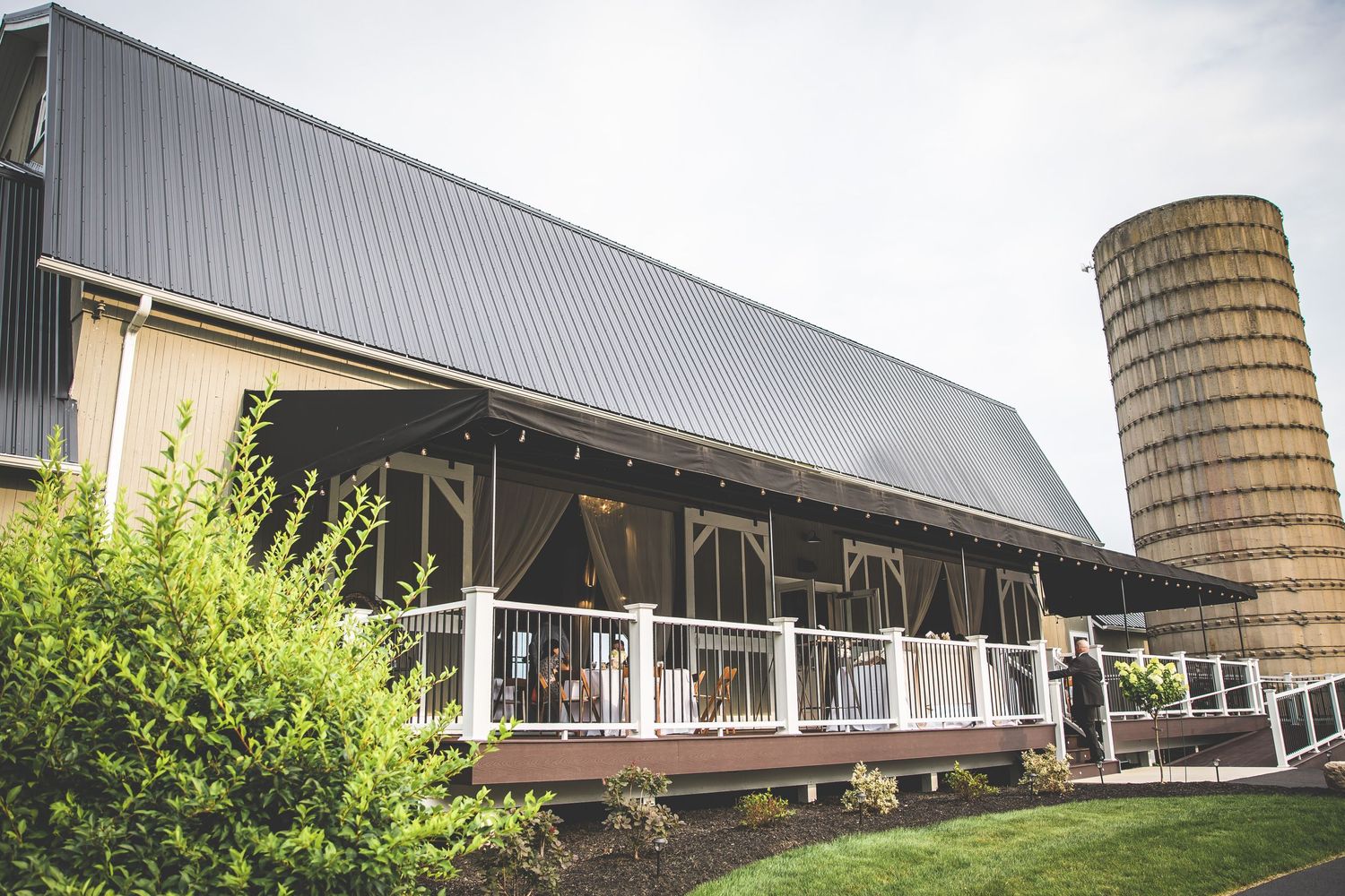 Rustic barn venue with modern metal roof and classic silo in countryside setting.