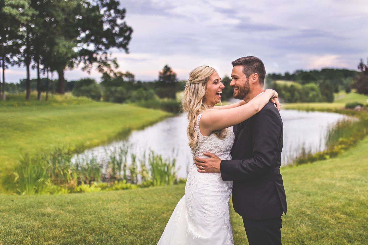 Couple embracing during outdoor wedding photoshoot by a serene lake.