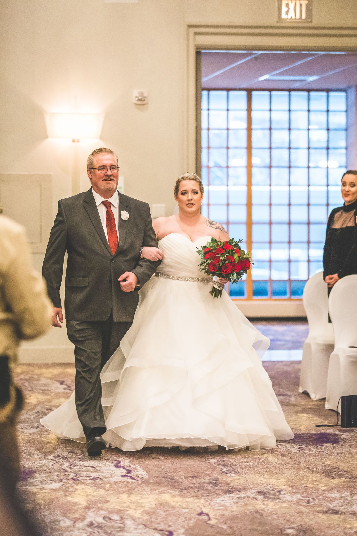 Wedding ceremony processional in an elegant indoor venue with purple carpeting.