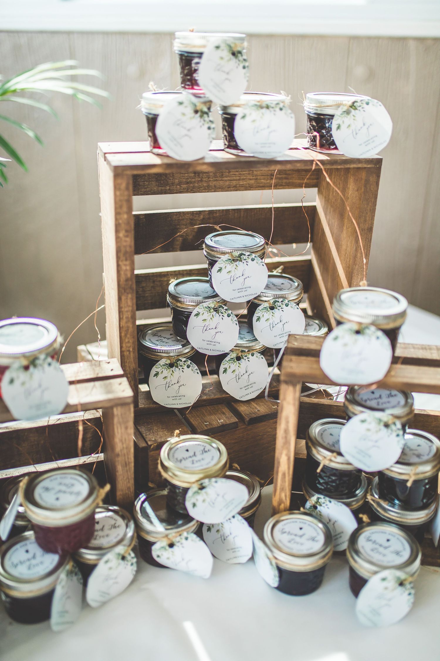 Rustic wooden display shelves holding mason jars decorated for wedding favors.