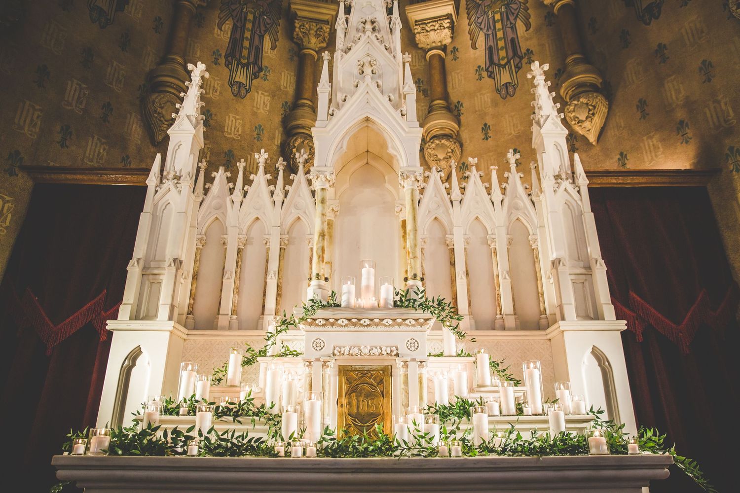 An ornate white cathedral altar decorated with floral arrangements for a wedding ceremony.