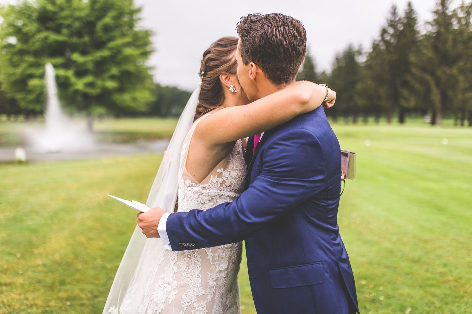An emotional moment shared between a couple reading personal vows with a fountain backdrop.