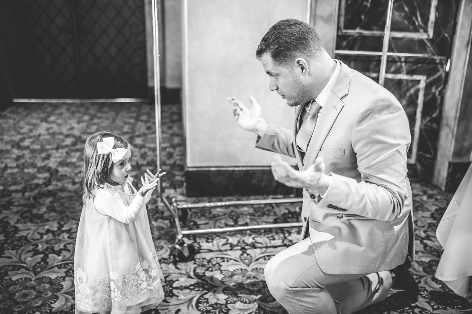 Sweet moment between man in gray suit and small girl in white dress.