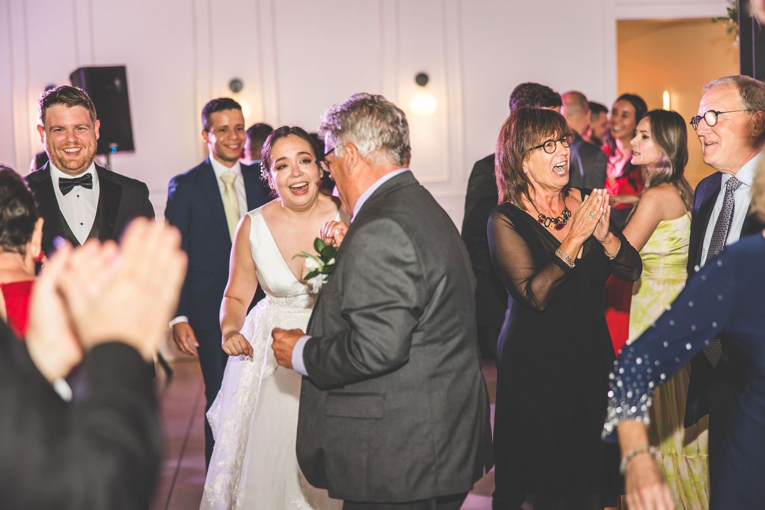 Wedding party and guests mingling and dancing at an elegant indoor reception.