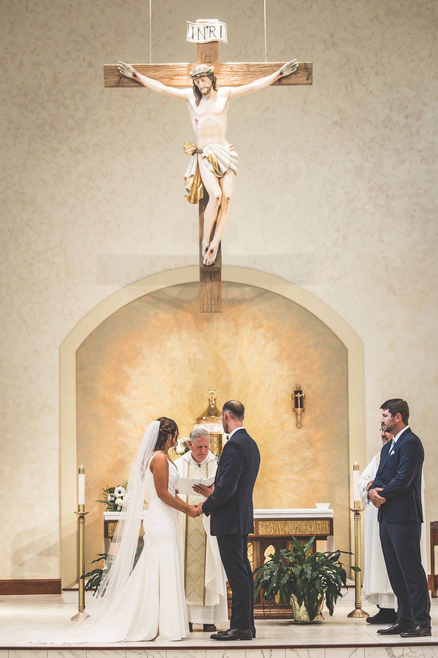 Wedding ceremony taking place beneath a crucifix in a modern church sanctuary.