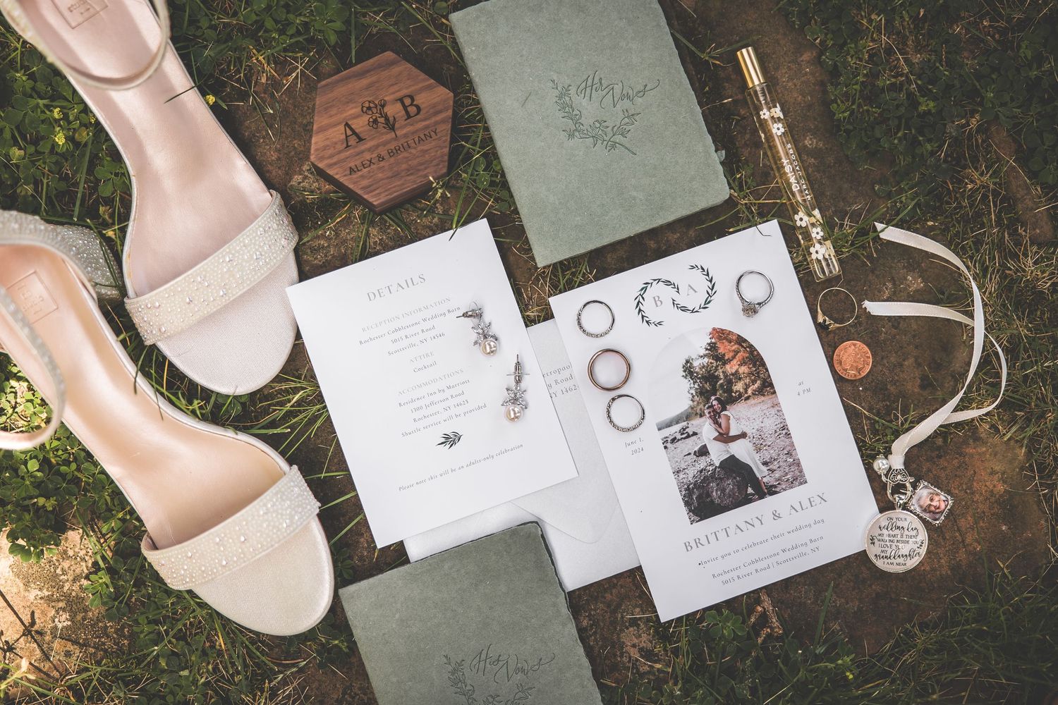 Wedding invitation suite and accessories arranged artistically on grass.