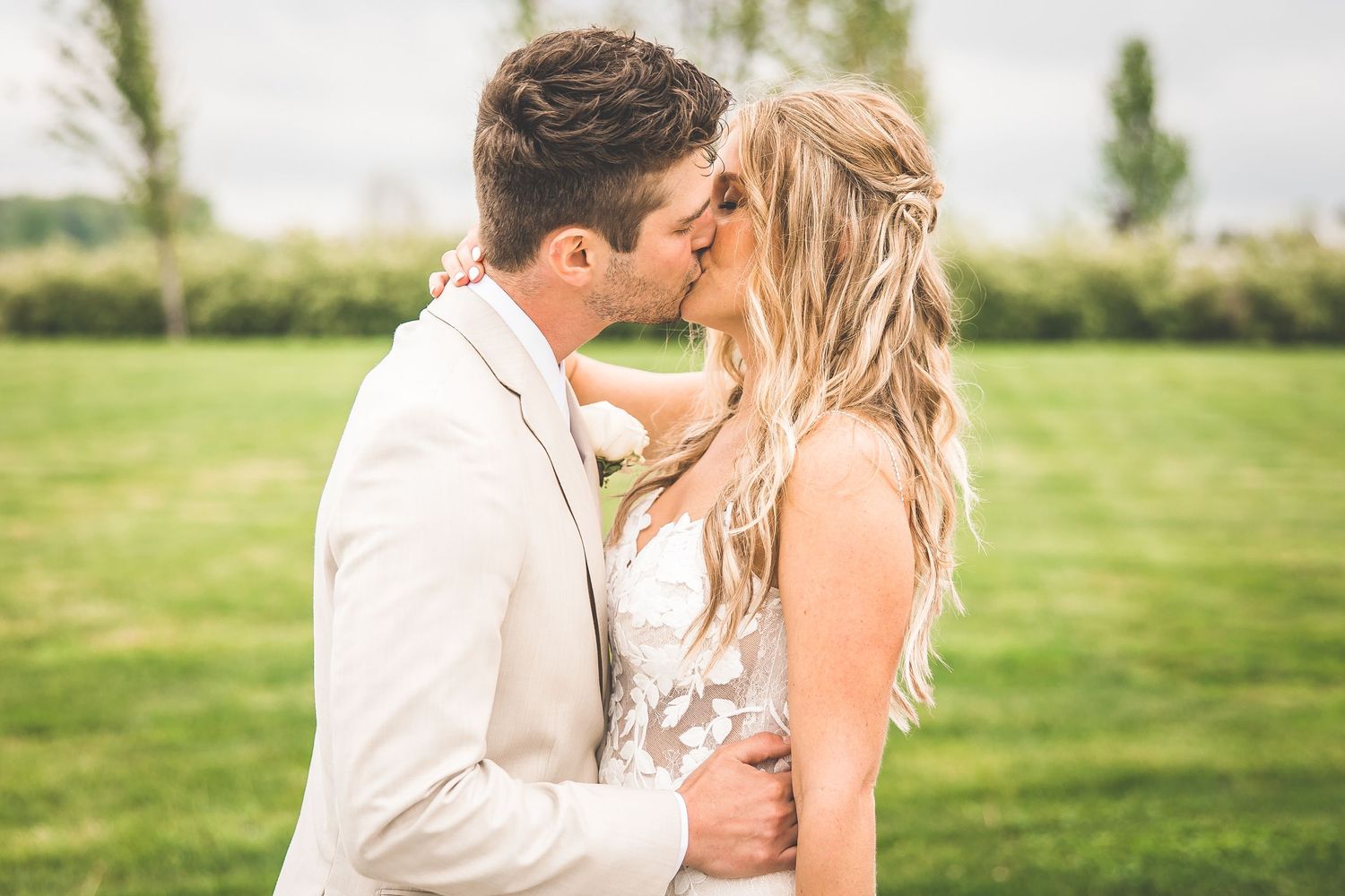 Newlyweds share an intimate moment against a scenic countryside backdrop.