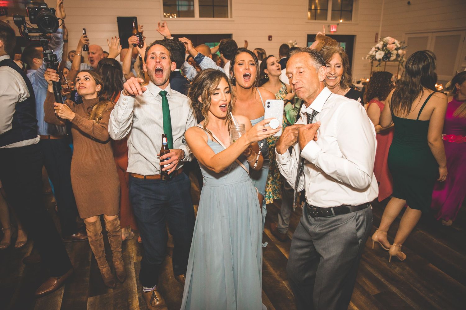 Wedding guests dance and celebrate on the dance floor during an indoor reception.