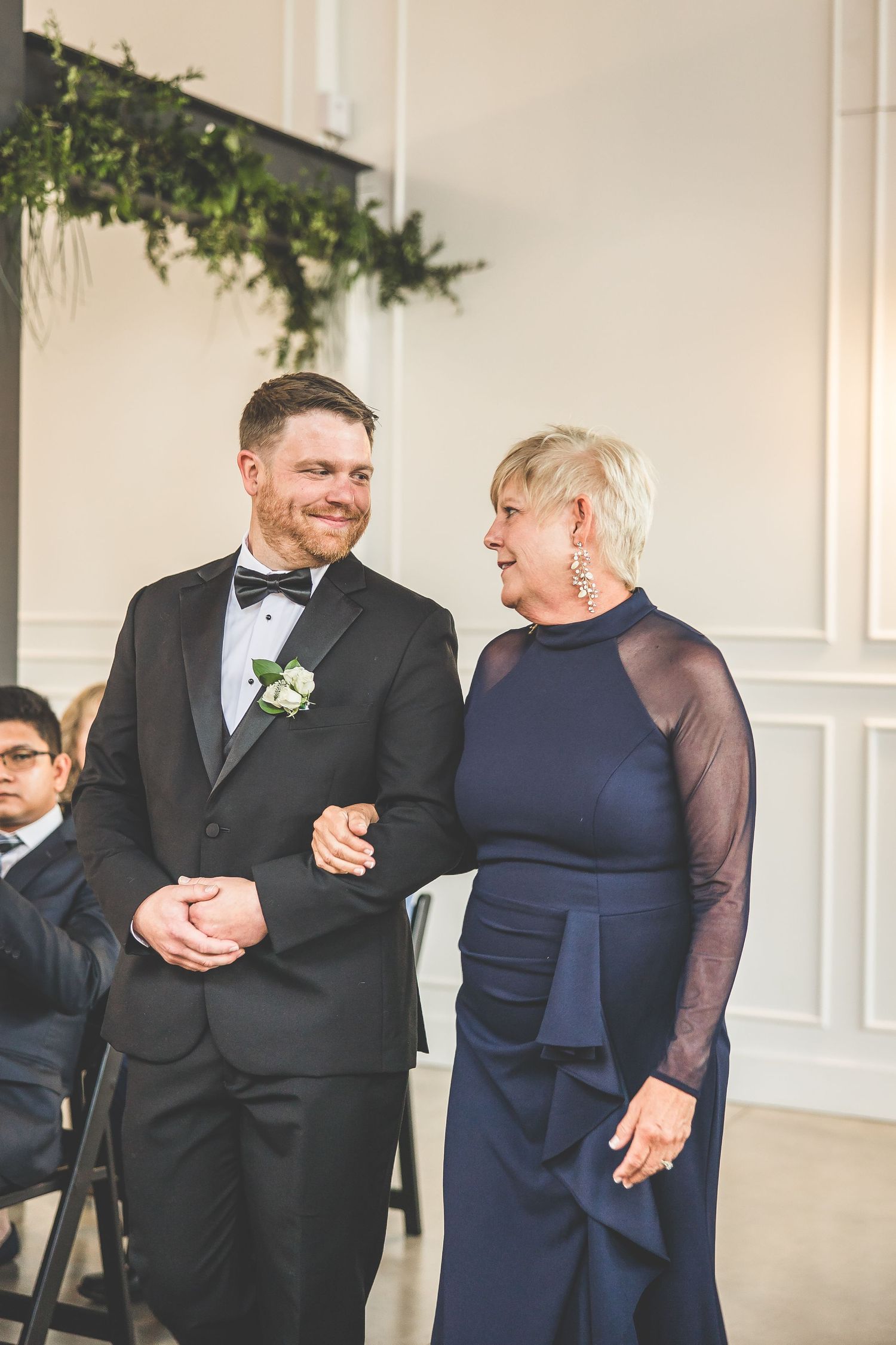 Wedding guests share candid moments during reception in formal attire.