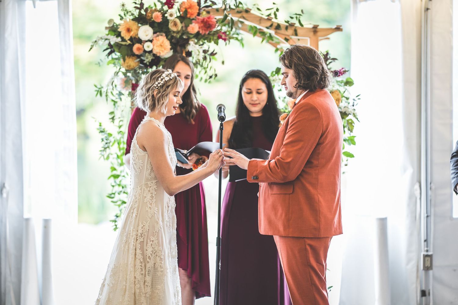 Intimate wedding ceremony moment under floral arrangements with rust and peach blooms.