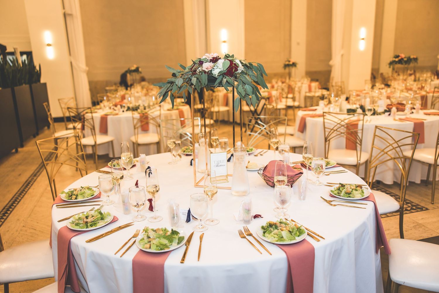 Elegant wedding reception setup with round tables, floral centerpieces and formal place settings.