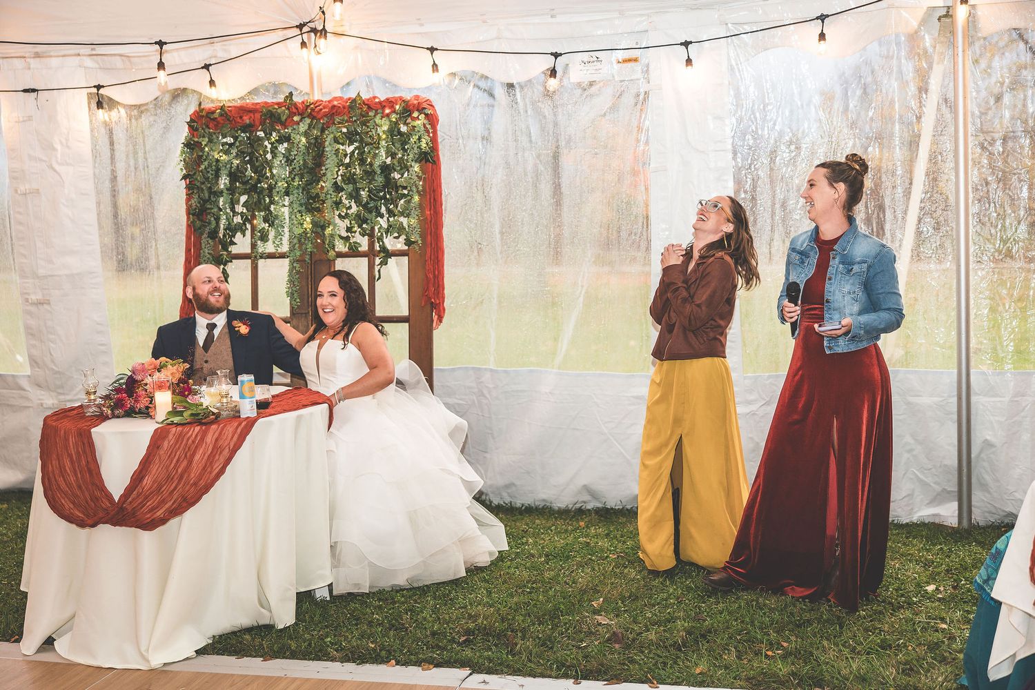 Outdoor tent wedding reception space with string lights and elegant white draping.