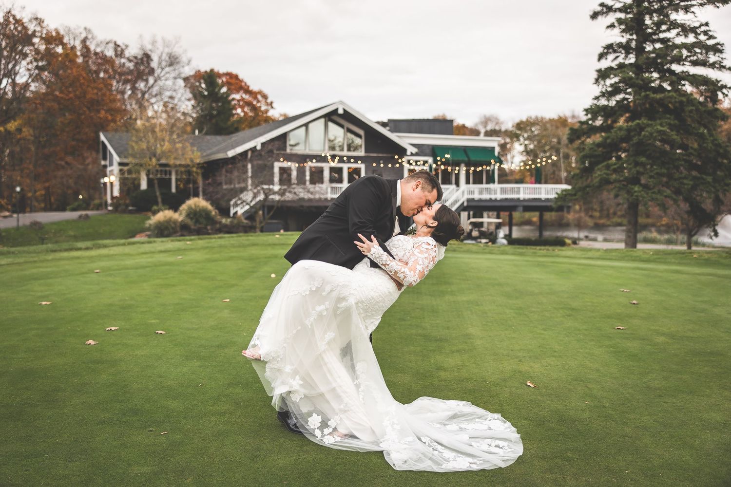 Newlyweds share tender moments on a golf course with fall foliage in the background.