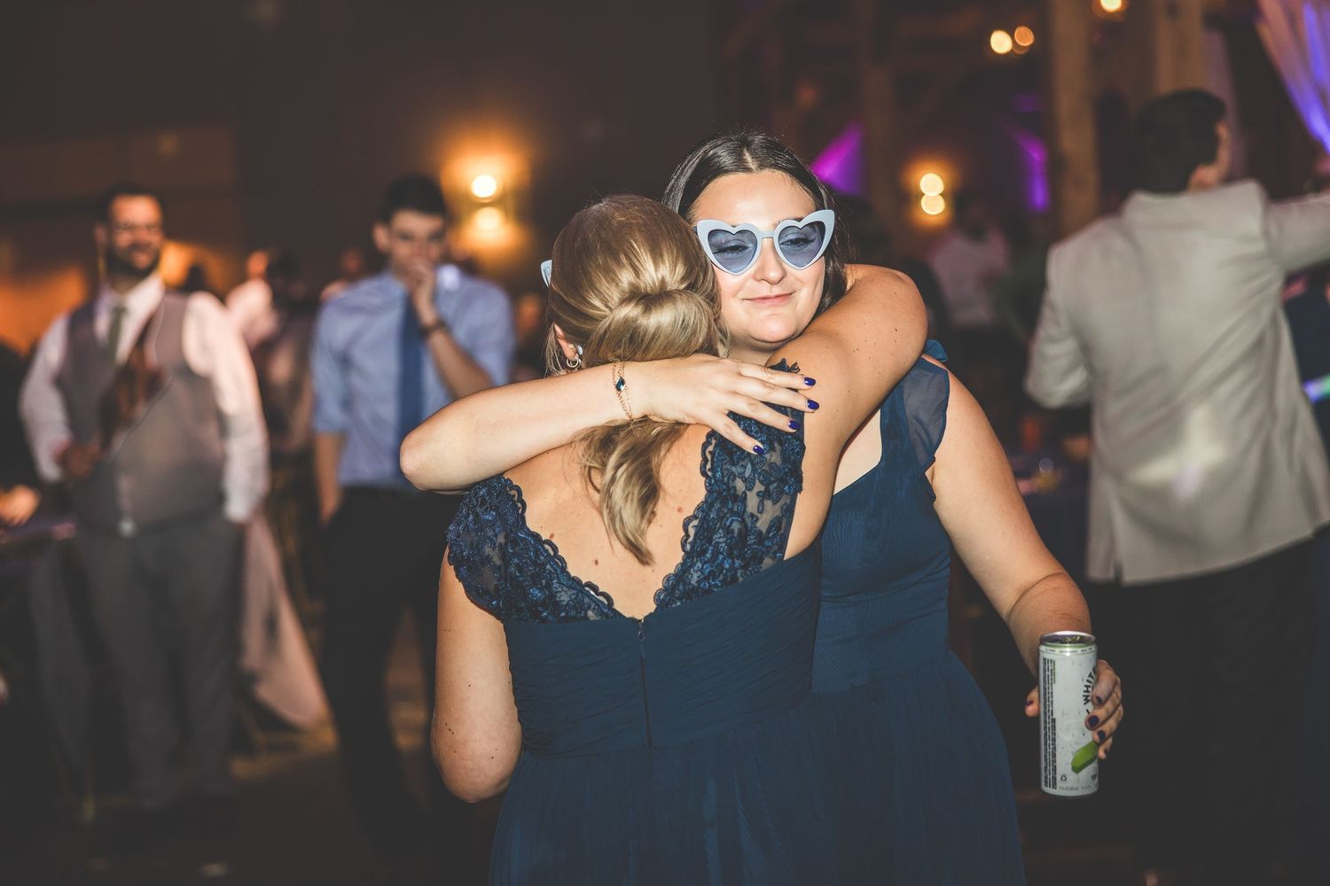 Wedding reception party guests dancing and socializing under atmospheric purple lighting.