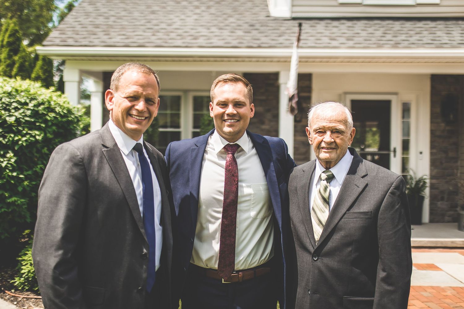 Groomsmen in navy suits and red ties gathered outdoors for wedding photos.