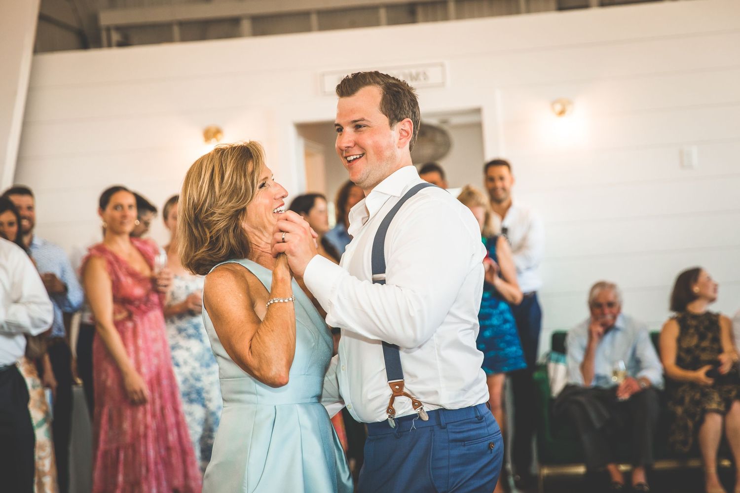 A couple shares an intimate dance moment at their wedding reception surrounded by guests.