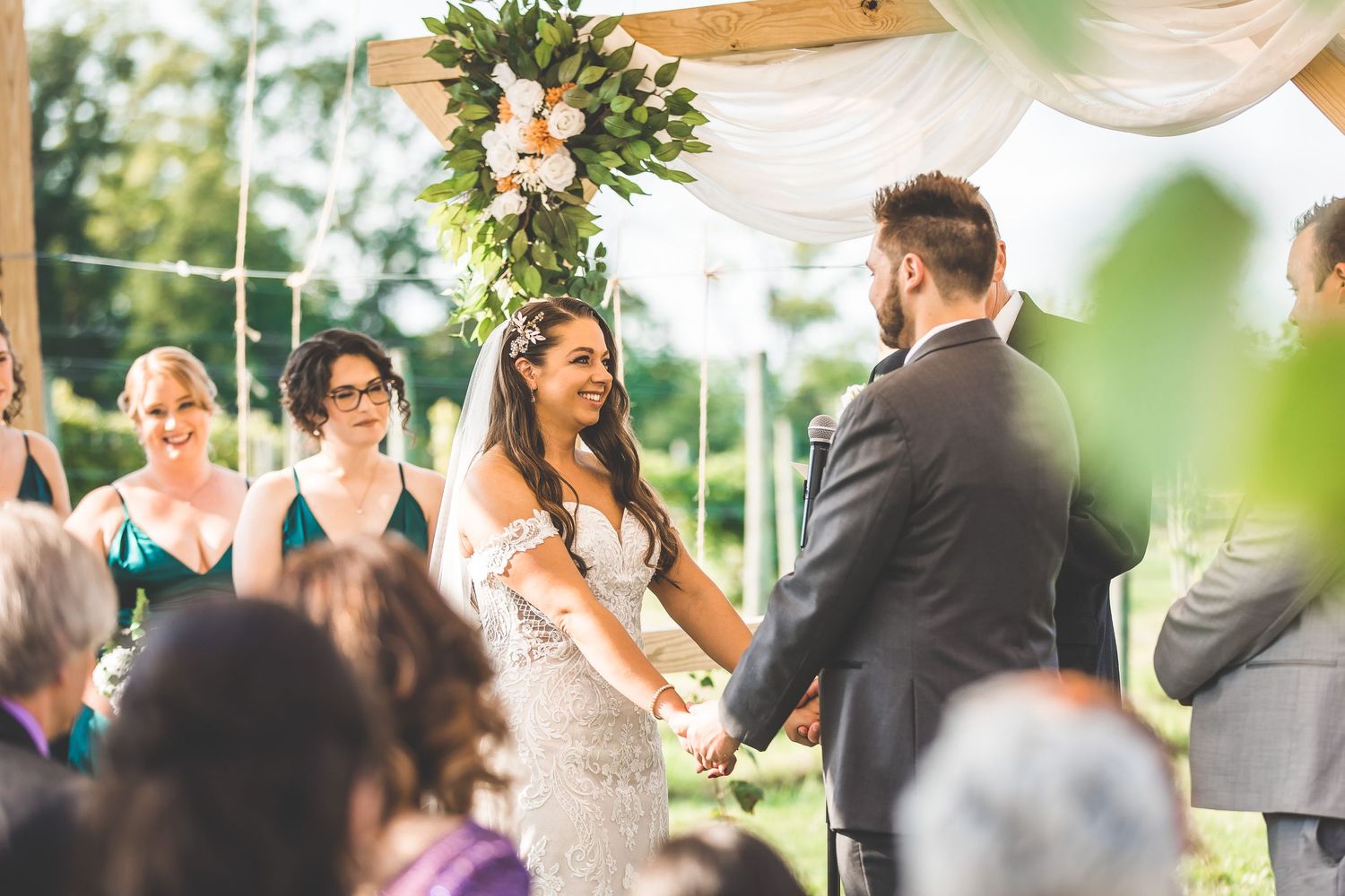 Emotional wedding ceremony moment captured under an outdoor pavilion with guests watching.