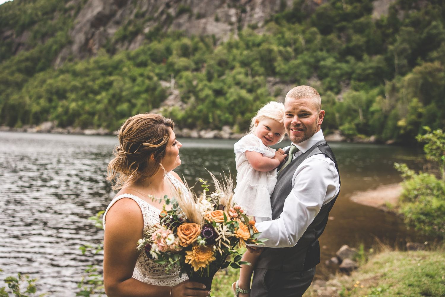 Romantic lakeside wedding photos with towering mountain cliffs in background.
