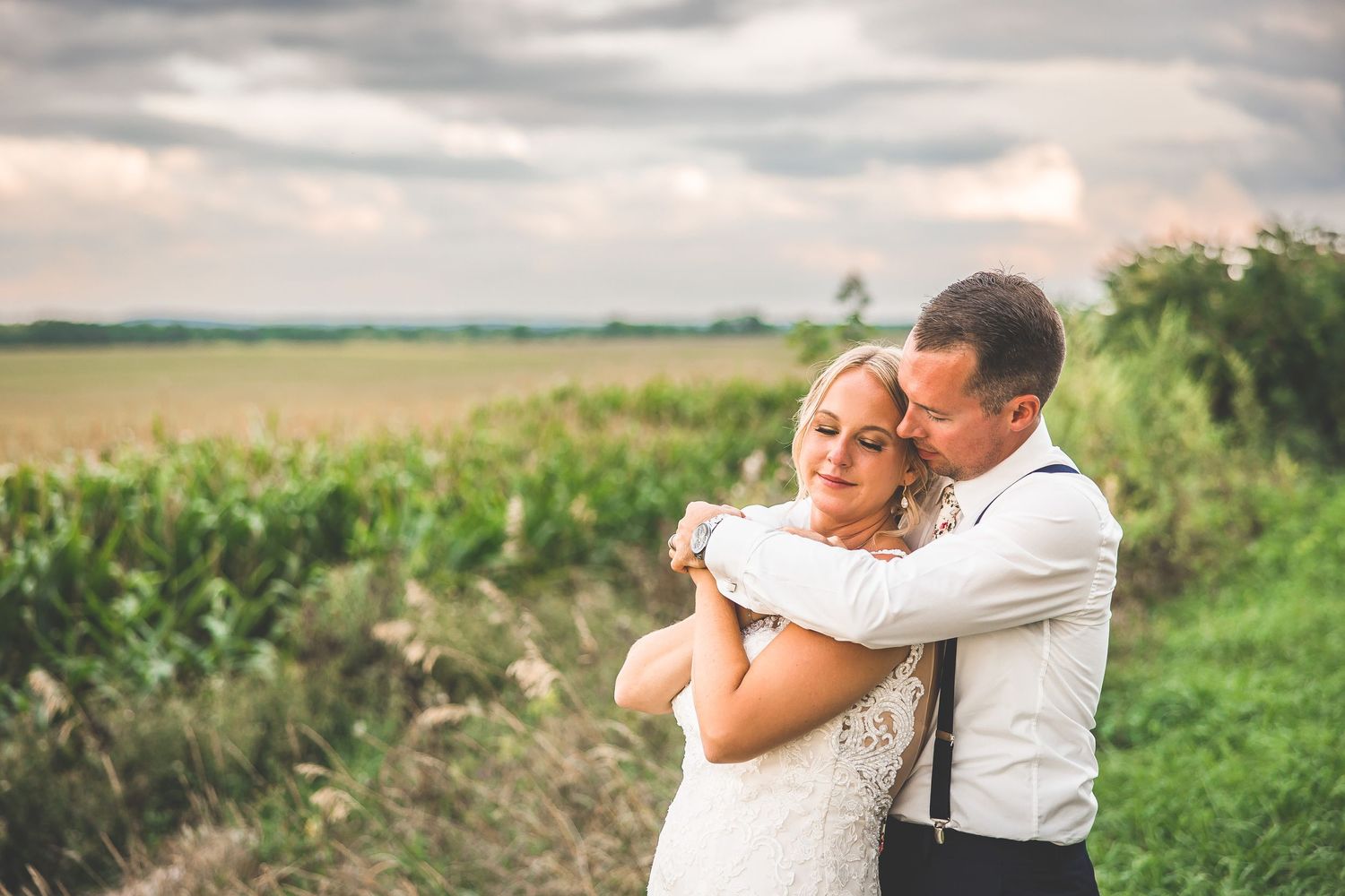 Intimate wedding portraits taken against a natural countryside landscape.