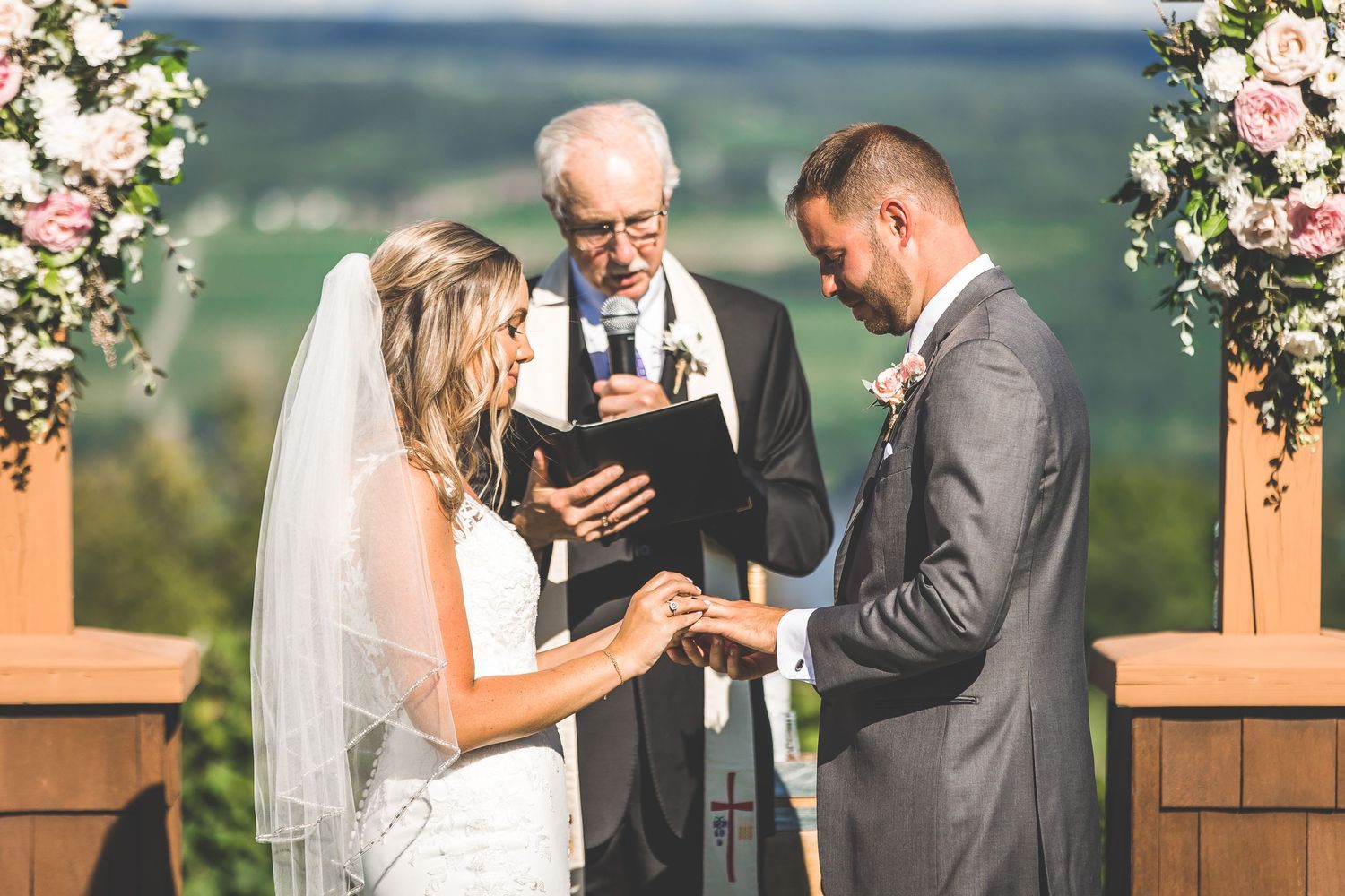 An intimate wedding ceremony moment under a floral arch with mountain vistas in the background.