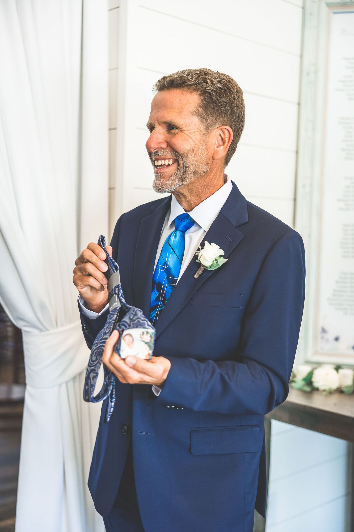 Two guests in navy suits share a lighthearted moment during the wedding celebration.
