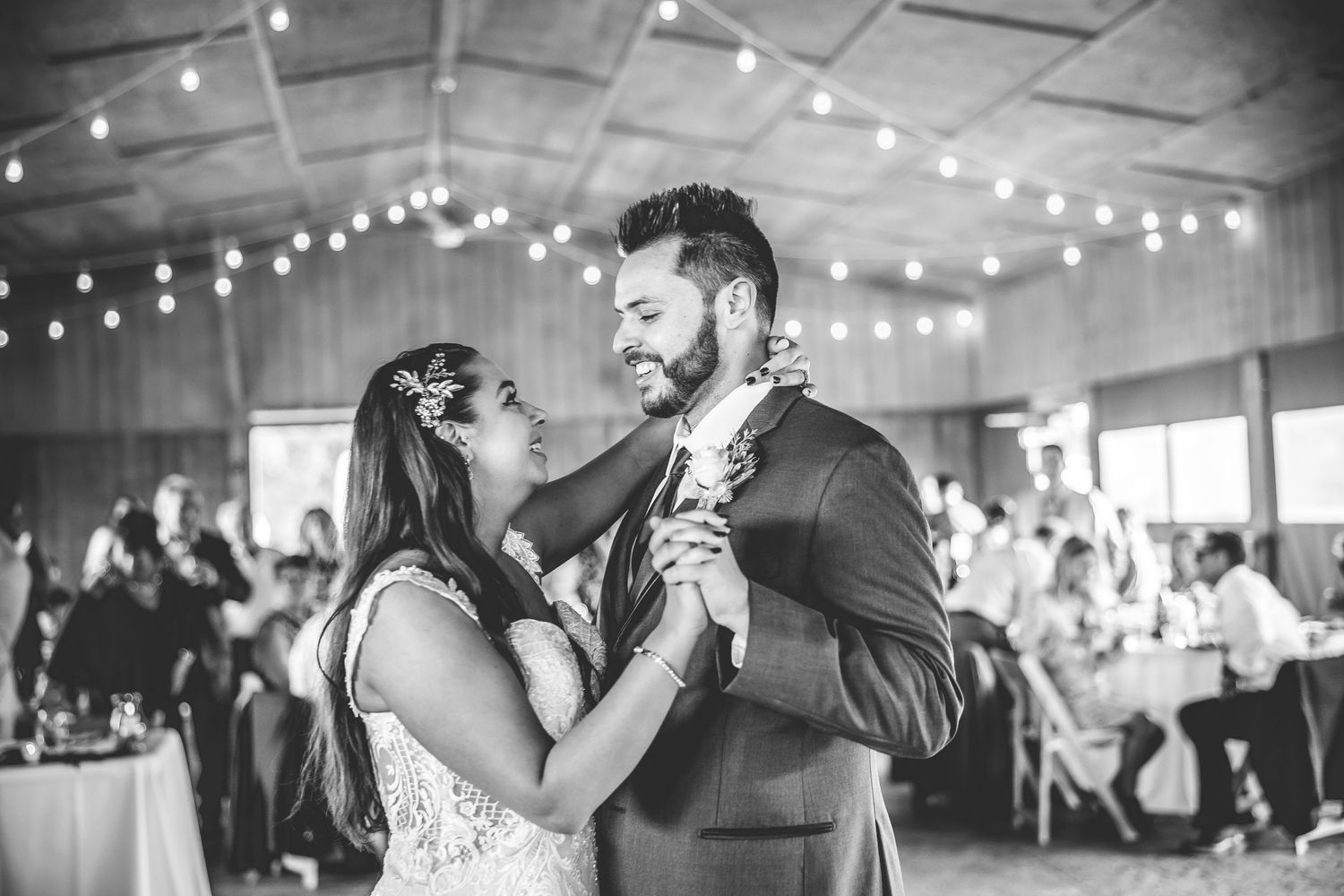 Black and white photos of wedding couple's first dance with guests watching in reception hall.