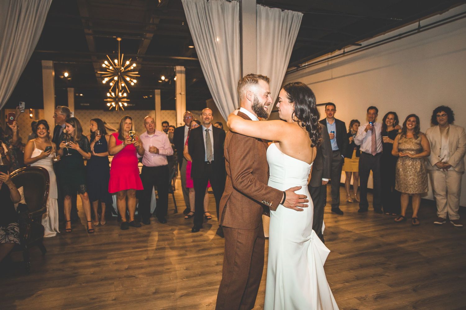 A couple shares their first dance surrounded by guests at an elegantly decorated venue.