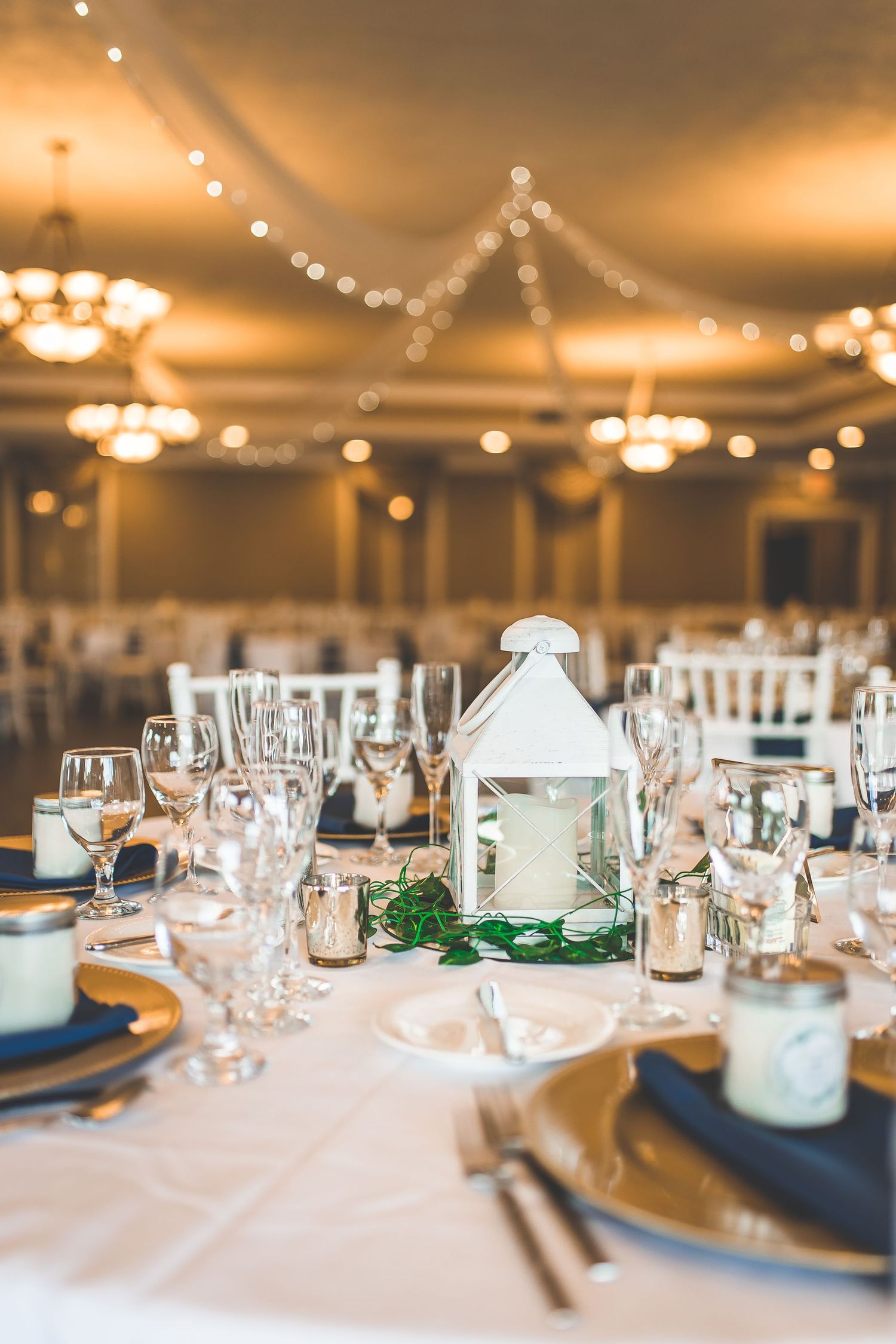 Elegant wedding reception table setting with string lights and navy blue accents.
