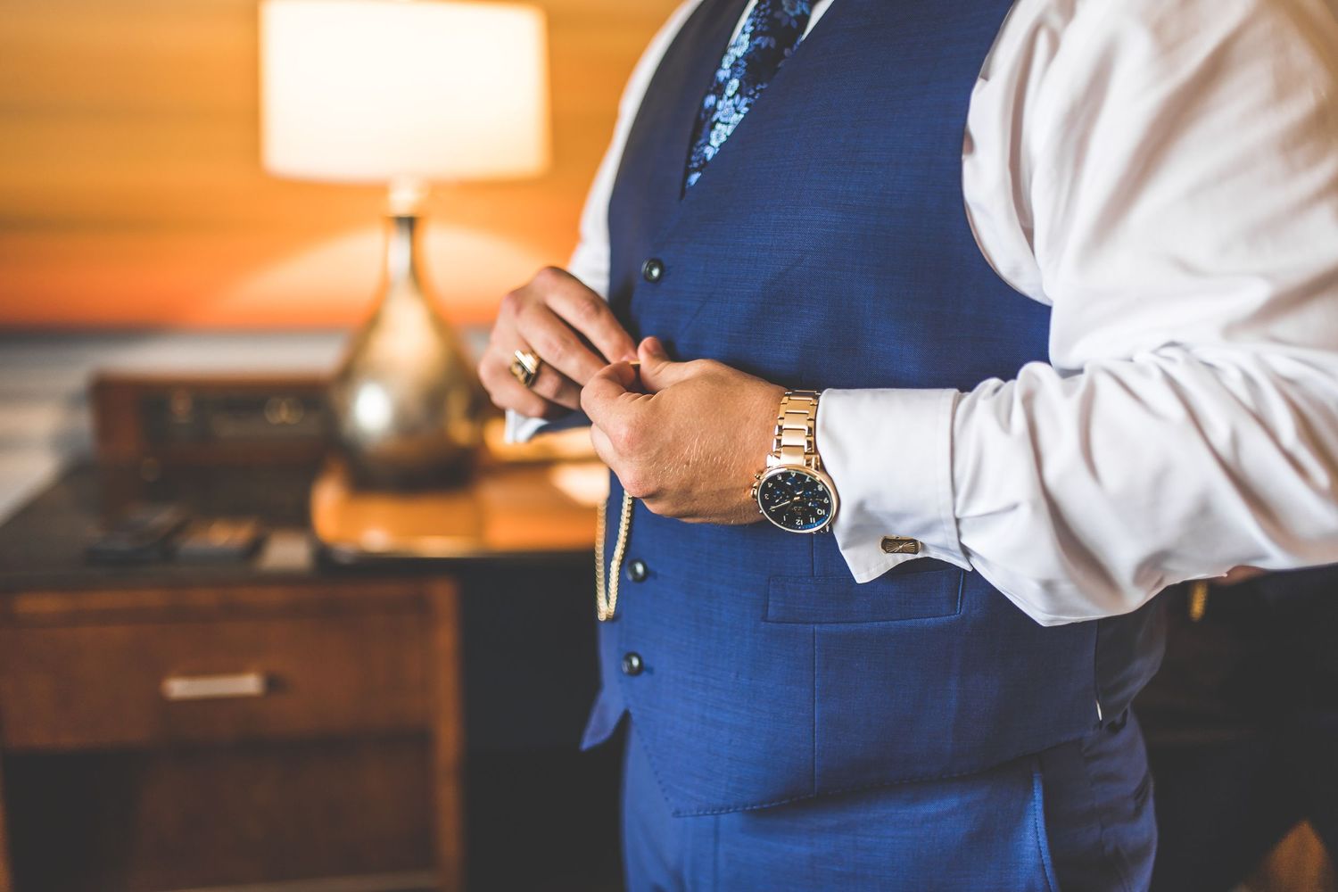 Close-up of formal blue suit vest and watch details during wedding preparations.