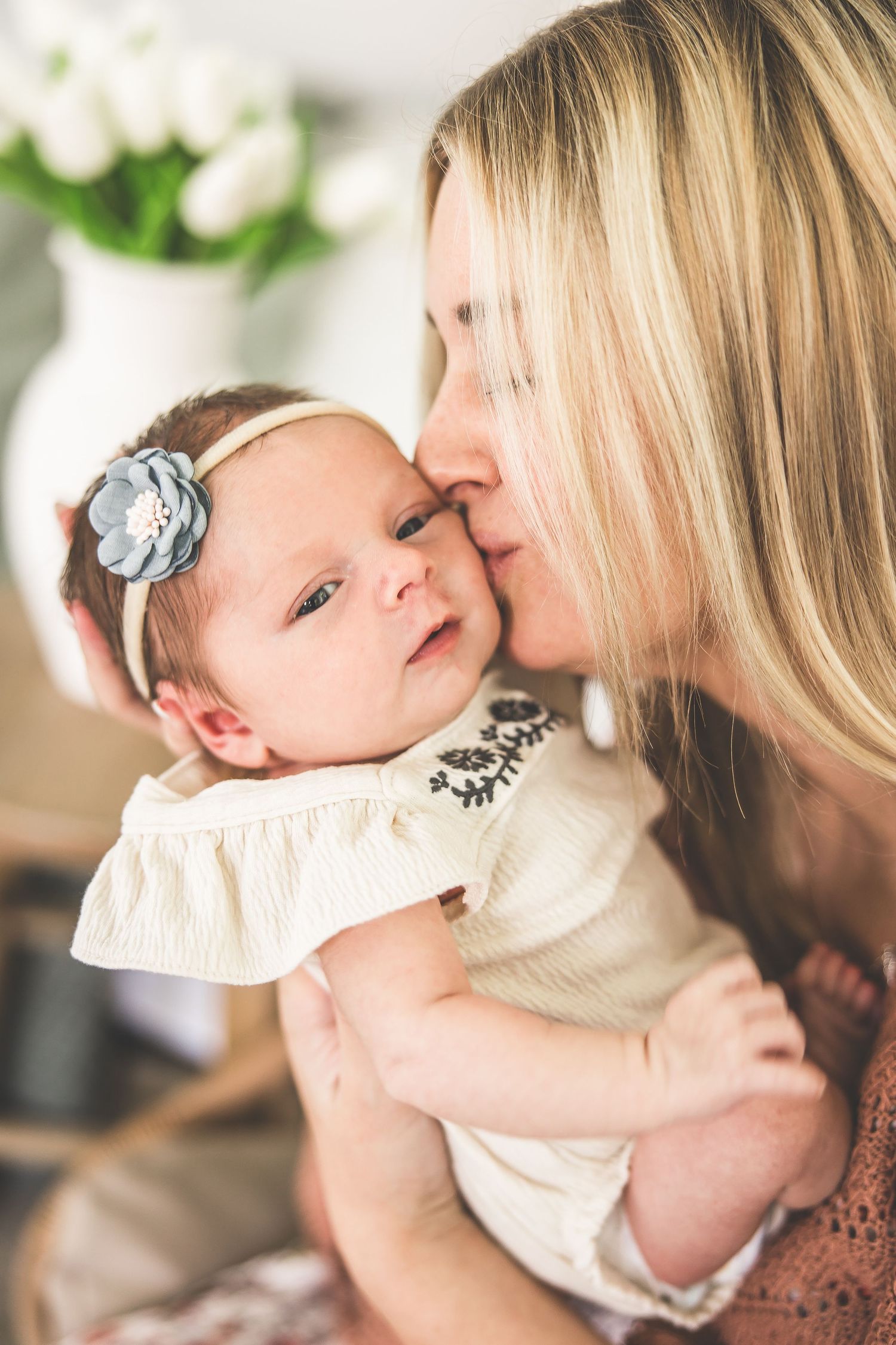 Gentle moments between mother and baby in cream-colored clothing against a bright background.
