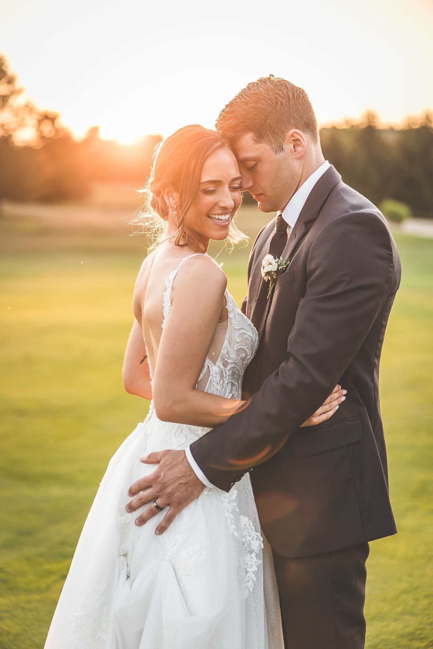 Golden hour wedding portraits in an open field at sunset.