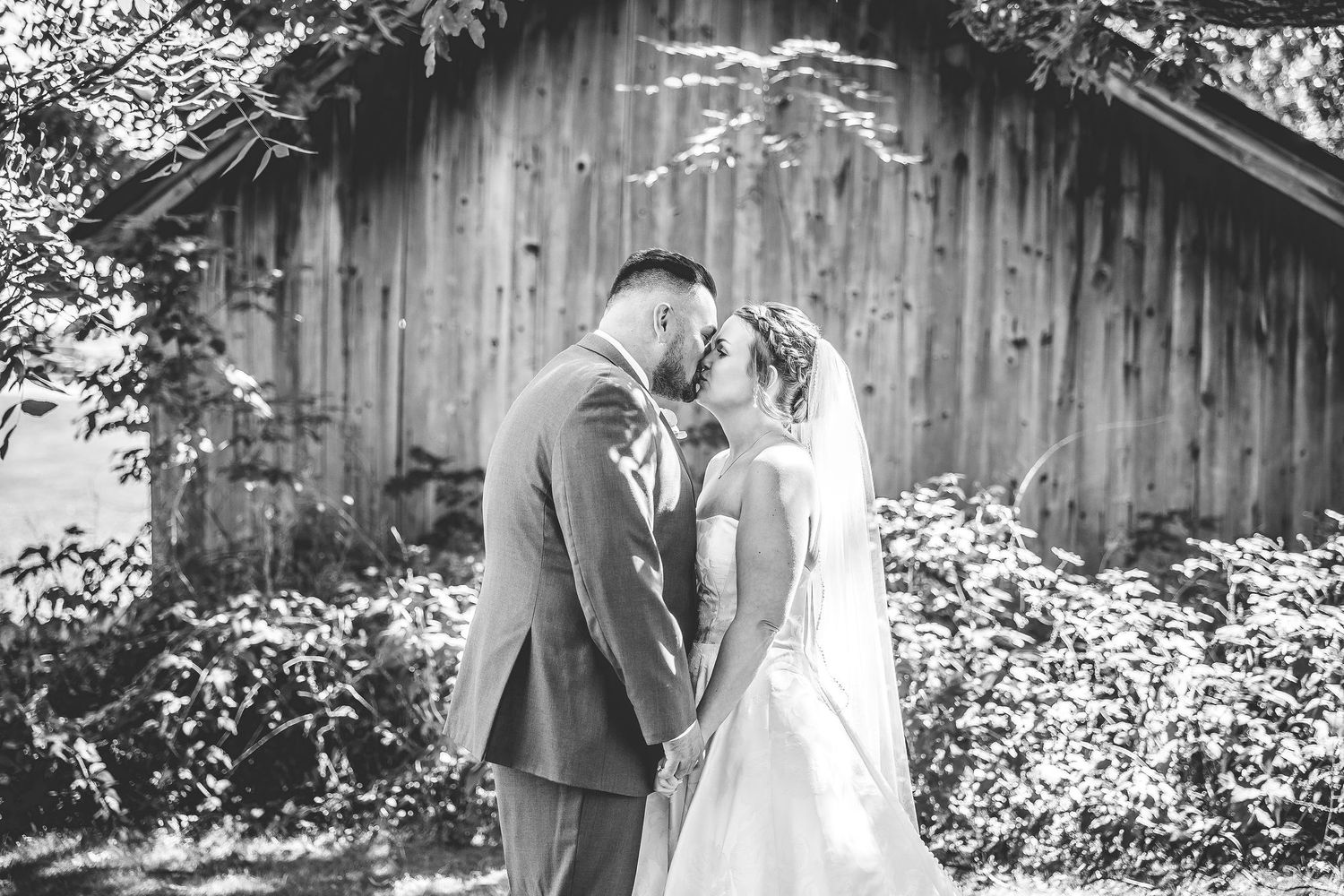 Black and white wedding photos showing tender moments against a rustic barn setting.