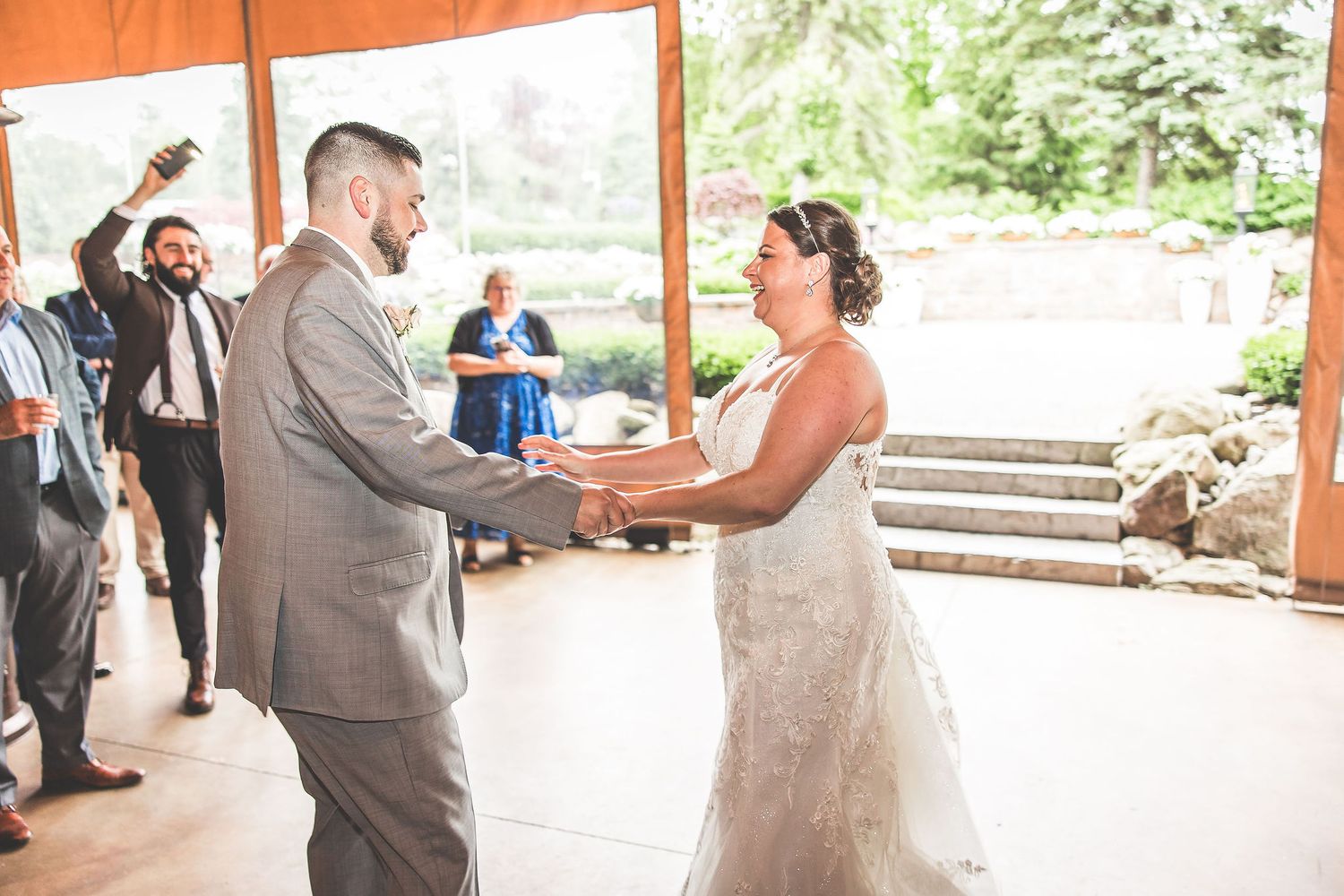 Wedding celebration under an orange-tinted pavilion with guests and decorations in natural lighting.